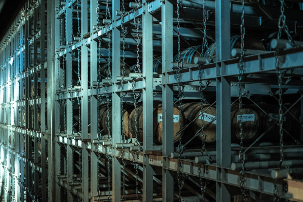 Ein großes Lagerhaus mit zahlreichen Fässern, die mit Metallstangen und Ketten verbunden sind und in einem ordentlichen Regalsystem angeordnet sind.