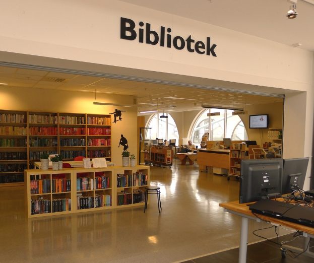 Holzregale voller Bücher, mit Monitoren auf der rechten Seite und dem Wort "BIBLIOTECA" oben angezeigt.
