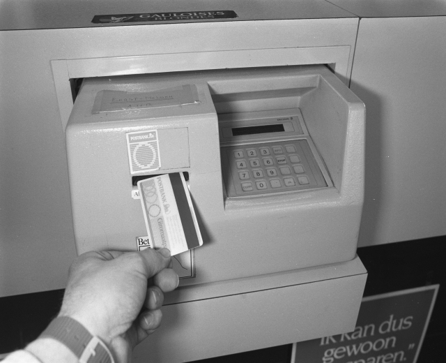 Eine Person steckt eine Karte in einen Geldautomaten