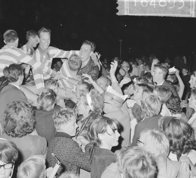 Ein Schwarz-Weiß-Foto einer Menge bei einem Konzert mit einer Gruppe von Menschen in der Mitte und Text in der rechten oberen Ecke.