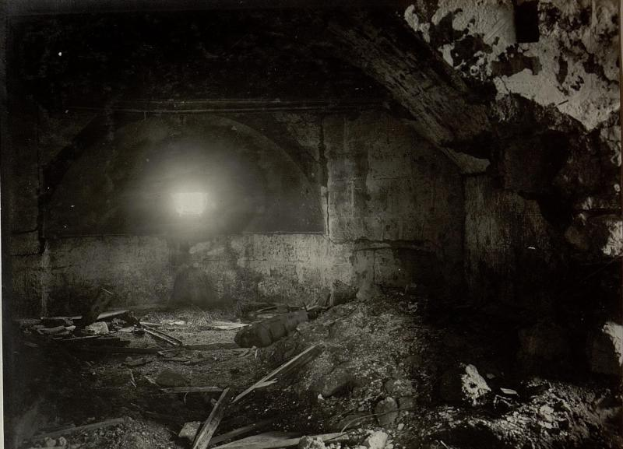 Ein altes Schwarz-Weiß-Foto eines zerfallenden Tunnels mit Schutt auf dem Boden und einem Licht am Ende, das sich in den Ruinen der Berliner Mauer befindet.