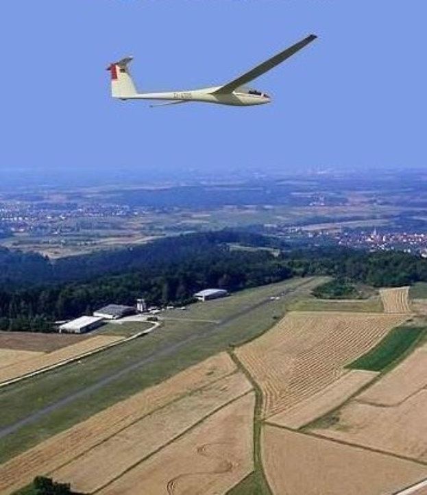 Segelflug über einem Feld mit Bäumen und Gebäuden im Hintergrund, mit Text oben im Bild.