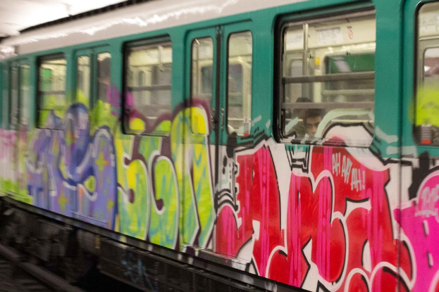 Ein Zug auf Schienen mit zwei Personen im Inneren und Graffiti an der Außenseite.