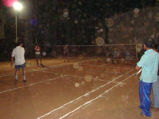 Eine Straßenlaterne befindet sich an der linken Ecke, mit ein paar Männern, die Volleyball auf dem Boden spielen.