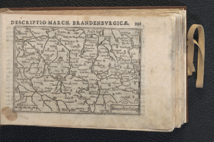 Ein offenes Buch, das eine detaillierte Karte der geografischen Merkmale von Brandenburg zeigt, liegt auf einer schwarzen Oberfläche.