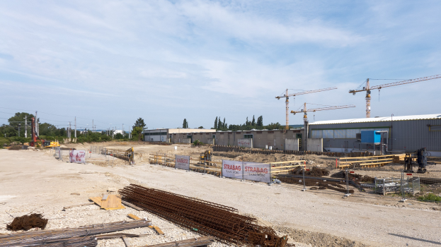 Baustelle mit verschiedenen Materialien, Geräten und Strukturen unter einem bewölkten Himmel.