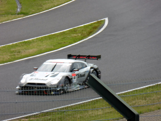 Audi R8 LMS GT3 Rennwagen auf der Nürburgring 24 Stunden Strecke positioniert, umgeben von einem Metallzaun und grünem Gras.