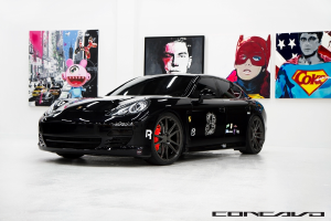 Ein schwarzer Nissan-Sportwagen mit Cartoon-Plakaten im Hintergrund und einem kleinen Zitat unten.