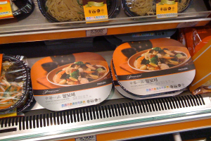 Lebensmittelboxen auf Regalen mit Preiszetteln.