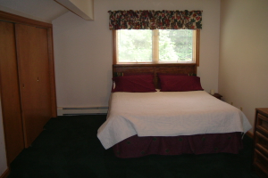 Ein Zimmer mit einem Schrank, einer Wand, einem Fenster und einem Bett.