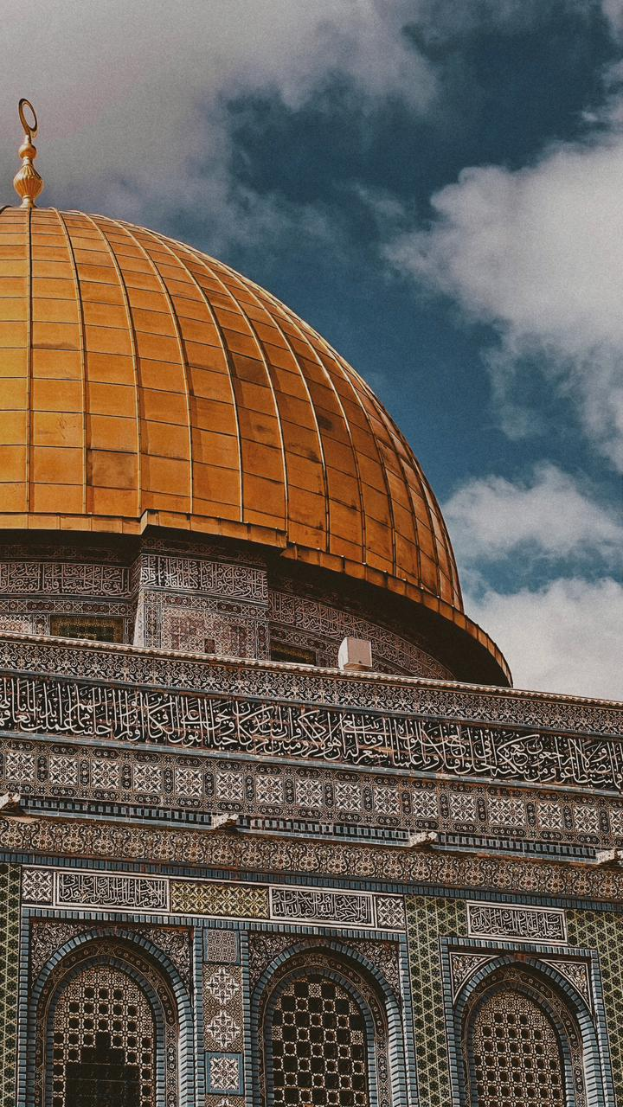 Die Felsendom in Jerusalem, Israel, ein großes Gebäude mit detaillierten Entwürfen und Texten an seinen Wänden, unter einem Himmel voller weißer, flauschiger Wolken.
