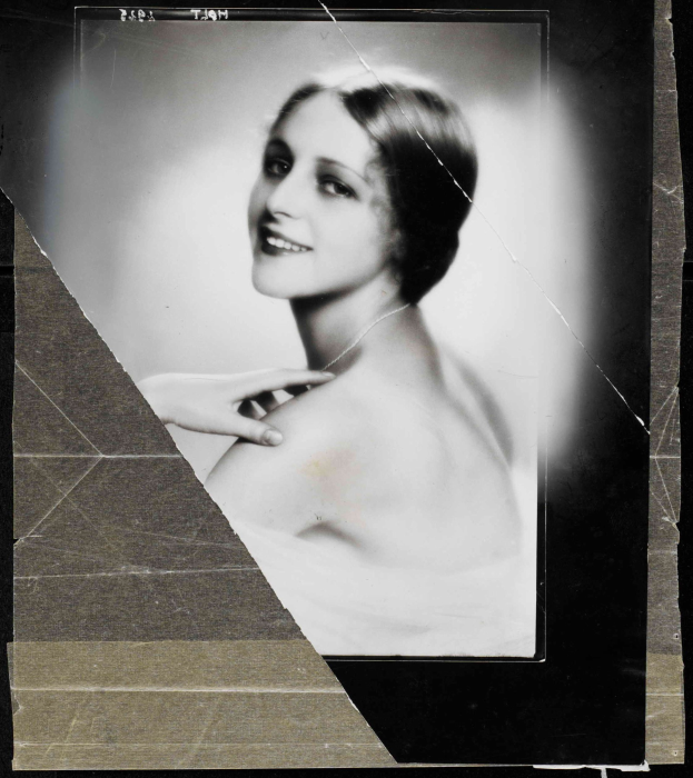 Schwarzes und weißes Porträt einer Frau in einem Kleid im Stil der 1920er Jahre mit einem ordentlichen Dutt, die warm in die Kamera lächelt.