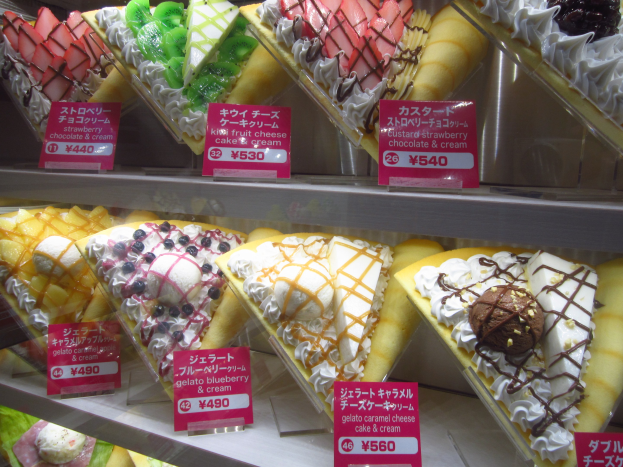 Eine Vitrine voller verschiedener Eiscreme-Sorten, jede mit einem Preisschild, in unterschiedlichen Farben, Formen und Geschmacksrichtungen.