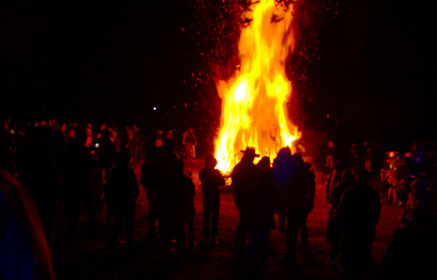 Eine Gruppe von Menschen, die vor einem Feuer stehen.