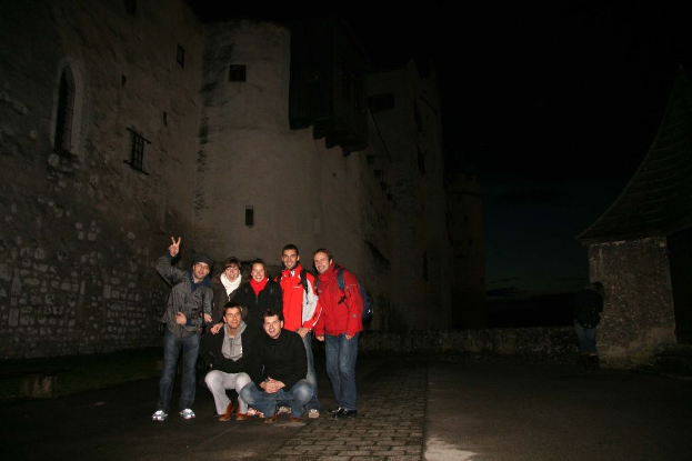 Menschen, die in der Mitte eines Bildes mit einer Burg im Hintergrund bei Nacht stehen.