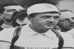 Ein Schwarz-Weiß-Foto eines Mannes in einer Mütze und Hosenträgern vor einer Gruppe von Menschen, der legendäre Fußballspieler sein soll.