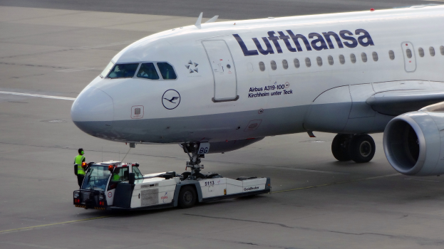 Ein Lufthansa Airbus A319-100 steht auf dem Rollfeld des Frankfurter Flughafens, mit einem Fahrzeug und einer Person in der Nähe, bereit zum Start.