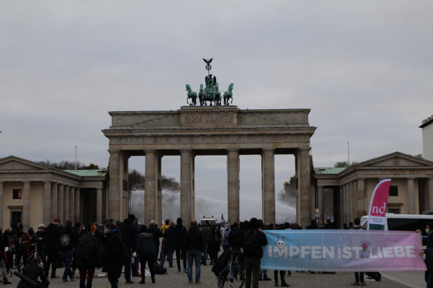 Gruppe von Menschen vor dem Brandenburger Tor in Berlin, Deutschland, mit Statuen, Säulen und umliegenden Gebäuden.
