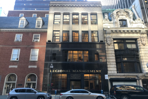 Eine Gruppe von Autos vor einem Gebäude mit Fenstern, Schildern, Straßenlaternen, einem Fahrrad und einem bewölkten Himmel, identifiziert als Regionalmanagement in New York City.