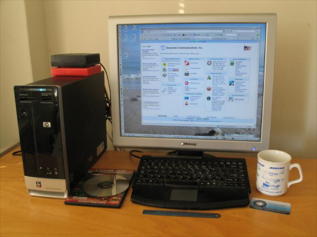 Ein Tisch mit einem Monitor, Becher, CPU, CD-Laufwerk und einer Klinge darauf.