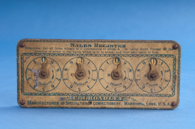 Ein altmodisches Verkaufsregister auf einem blauen Hintergrund mit Text und Zahlen, die das Datum und die Uhrzeit angeben.