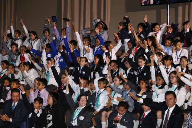 Schwarzes und weißes Foto einer Familie aus drei Personen - einem Mann, einer Frau und einem Kind - auf einem Sofa sitzend mit einem Fernseher davor.