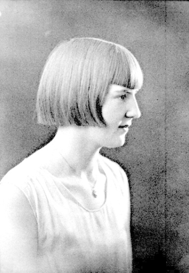 Ein Schwarz-Weiß-Foto einer Frau mit einem kurzen Bob-Haarschnitt, ihr Gesicht ist deutlich zu sehen, mit zur Seite schauenden Augen und leicht geöffneten Lippen.