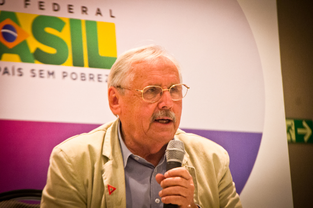 Eine Person, die in ein Mikrofon spricht und hinter sich ein Banner mit der Aufschrift 'Bundes' hat.