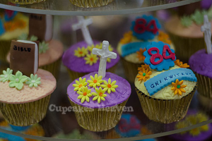 Ein Buch und ein heiliges Kreuz-Symbol sind auf einem Cupcake drapiert, mit anderen Cupcakes im Hintergrund.