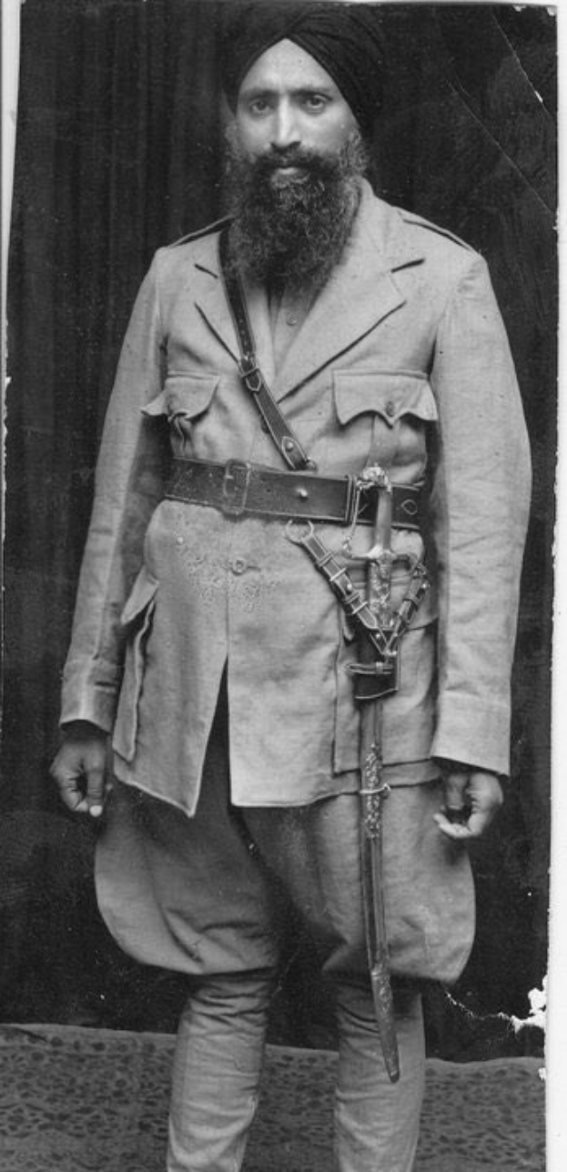 Schwarz-weißes Porträt eines Mannes mit langem Bart, der einen Turban trägt und ein Schwert hält, identifiziert als Guru Nanak Dev Ji.