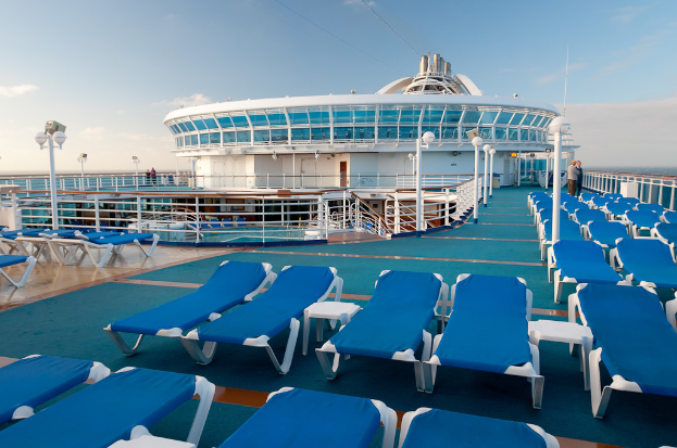 Sonnenliegen auf einem Fährdeck mit Geländer, Architektur und Himmel im Hintergrund.
