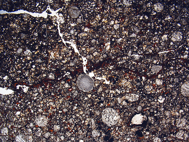 Nahaufnahme einer gesprungenen, schmutzbedeckten Straße mit rauer, unebener Oberfläche.