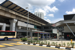 Ein Bus parkt vor dem Singapur-Changi-Flughafen, einem Gebäude mit Säulen und Dach, umgeben von Pflanzen, einem Metallzaun, Menschen, Fahrzeugen, einem Schild, einem Straßenschild, anderen Gebäuden und einem bewölkten Himmel.