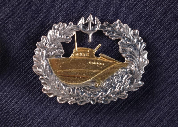 Ein goldener und silberner deutscher Marineorden mit einem Boot darauf, auf einem Tuch präsentiert.