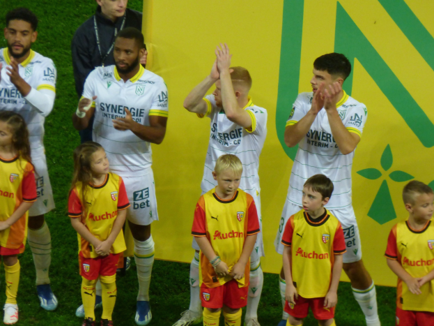 Eine Gruppe von Fußballspielern in Uniform klatscht nach einem Sieg auf einem Ligue-1-Feld.