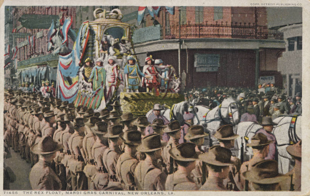 Eine alte Postkarte zeigt einen Mardi-Gras-Umzug in New Orleans mit einem geschmückten Wagen, Reiter und Zuschauern an der Straße mit Gebäuden im Hintergrund.