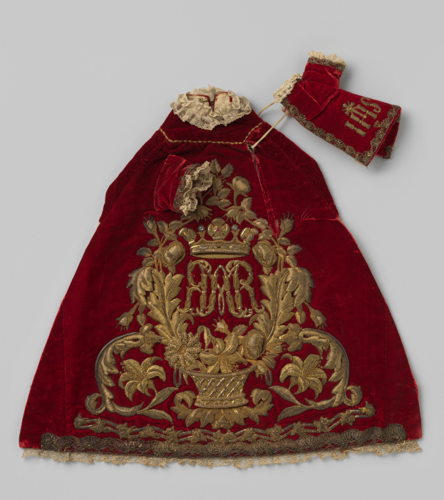 Ein roter Samtmantel mit goldener Stickerei und einer Krone, der gegen einen weißen Hintergrund gestellt ist und detaillierte Verzierungen aufweist.