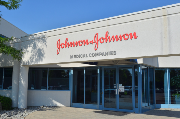 Außenansicht des Johnson & Johnson Medical Companies-Gebäudes mit Glaswänden, einem Baum und Pflanzen auf der linken Seite und einem klaren blauen Himmel im Hintergrund.