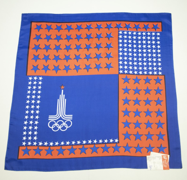 Ein blaues und oranges Tuch mit dem Olympischen Logo, vor einem weißen Hintergrund.
