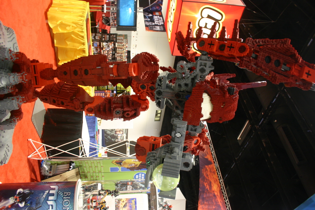 Ein Roboter steht in der Mitte eines Raums mit Boxen im Hintergrund, Teppich auf dem Boden und einer Decke über ihm.