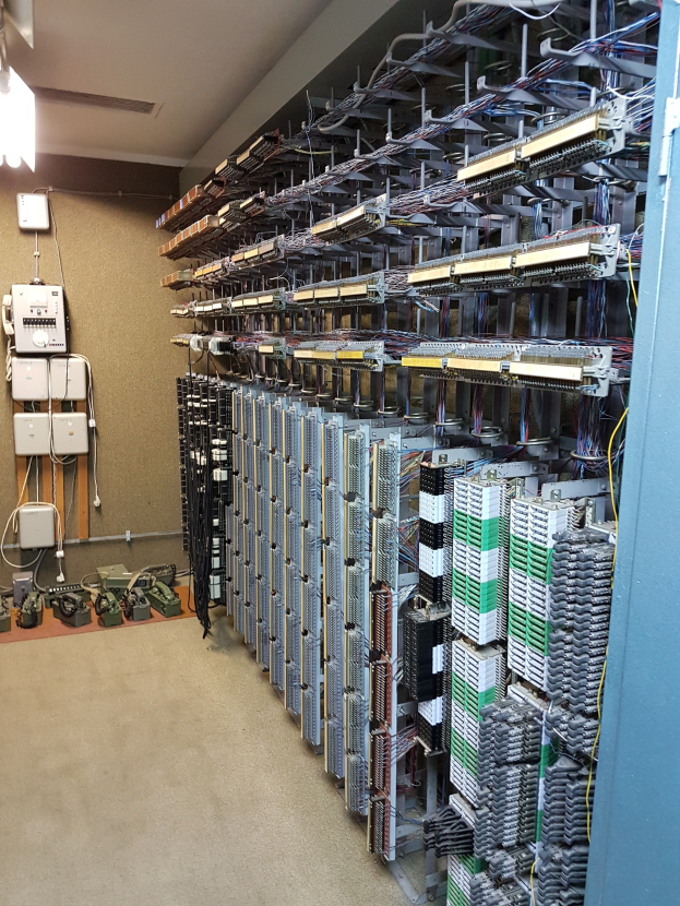 Großer Raum voller Server, Kabel und elektronischer Geräte, typisch für ein Rechenzentrum.