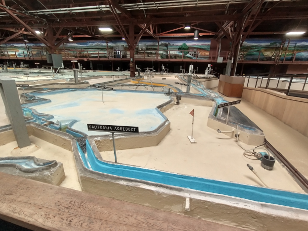 Großer Indoor-Wasserpark mit mehreren Wasserrutschen, Deckenleuchten, Wandgemälden und Minigolfplatz.